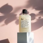 A funny bubble bath bottle on a podium with a pink leaf shadowy background