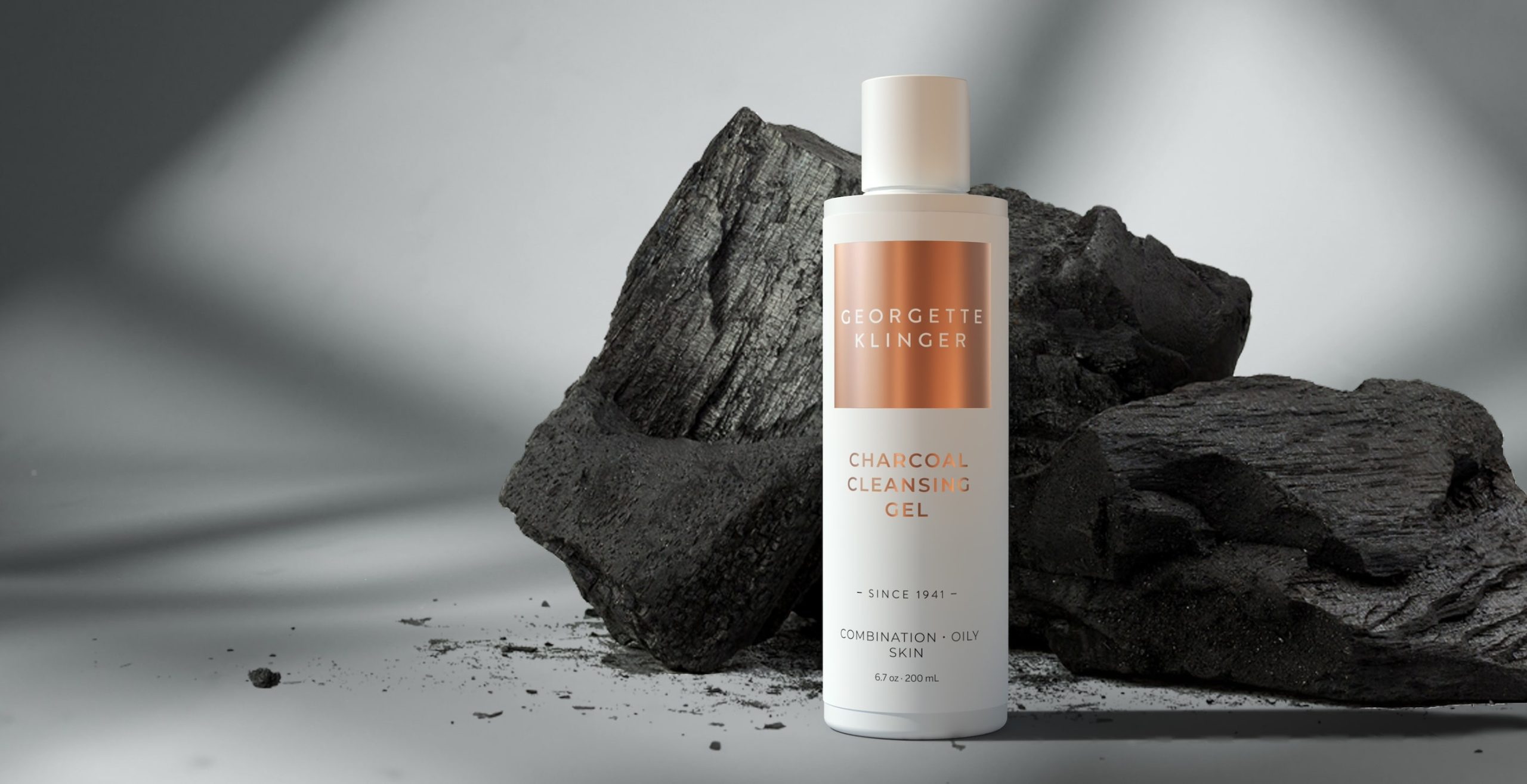 A 3D rendered women's skincare product bottle standing in front of two large charcoal bricks