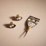 Matching suit pin and fan earrings flatlay on a beige background.